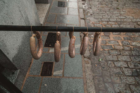 A high angle view of kielbasas hanging from a pipe outdoors under the lightsの写真素材