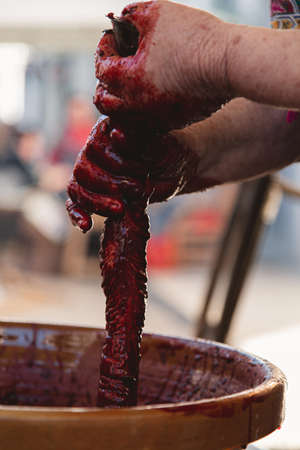 A vertical closeup of a person with dirty hands making a kielbasa in a clay pot under the sunlightの写真素材