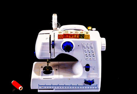 An old white sewing machine with a black background