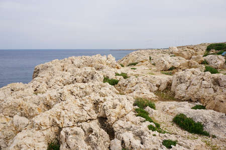The mesmerizing view of the rocks in the shore of a calm ocean under the blue sky