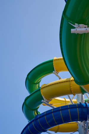 A vertical low angle view of colorful slides in an amusement park under the sunlight and a blue sky
