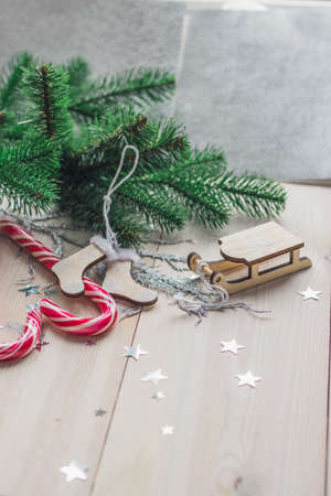 A vertical picture of candy canes and Christmas decorations on a wooden table under the lightsの写真素材