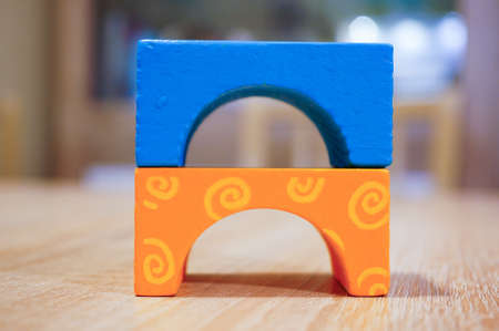 A closeup of small colorful toy figures on a wooden table under the lights with a blurry background