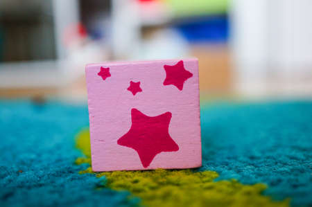 A pink square toy with stars on its surface put on a multicolored surfaceの写真素材