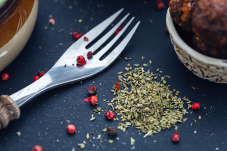 A selective focus shot of a fork with fresh spices laid in a dark surface