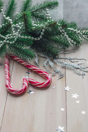 A closeup of Candy canes surrounded by Christmas decorations on the table under the lightsの写真素材
