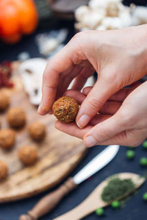 A vertical shot of a person preparing a vegetable meatball with a blurred backgroundの写真素材