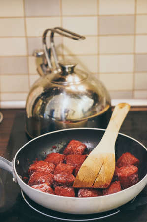A pan of meat being cooked over the stove in the kitchenの写真素材