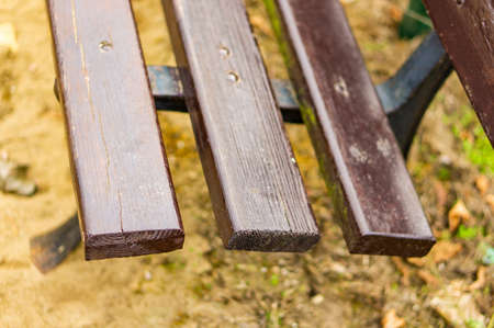 A closeup shot of a wooden bench in the park during daytimeの写真素材