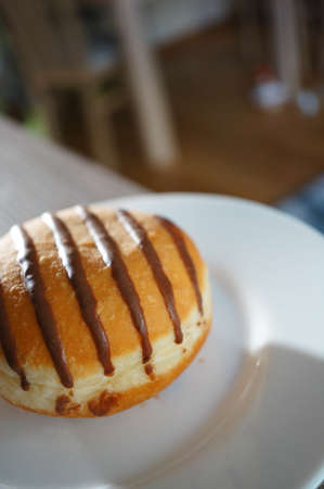 A doughnut with chocolate on its surface put on a white plate