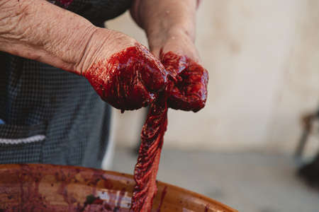 A closeup of a person with dirty hands making a kielbasa in a pot under the lightsの写真素材