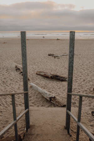 A vertical picture of a beach surrounded by the sea under a cloudy sky during the sunsetの写真素材