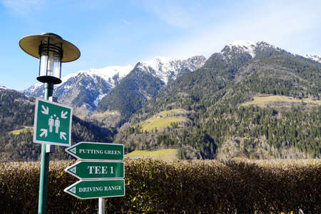 Golf resort signs indicating  assembly point and directions with majestic mountains in the...