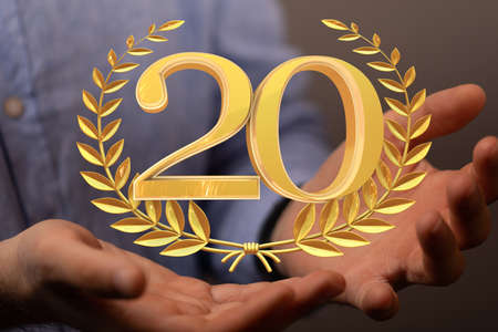 The golden number 20 and spikes of wheat over someone's handsの写真素材