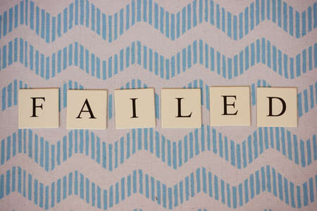 The word failed written by letters on small squares on a blue and white pattern
