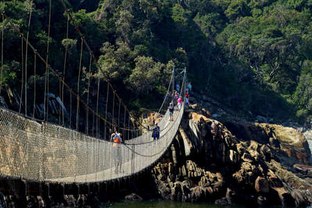 STORMS RIVER, SOUTH AFRICA - Apr 15, 2019: Tourists walking over one of the many suspension bridges at the Stormsriver mouth. This is a popular tourist attraction.のeditorial素材