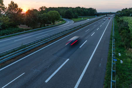 german highway at sunset with light trails from passing carsの写真素材