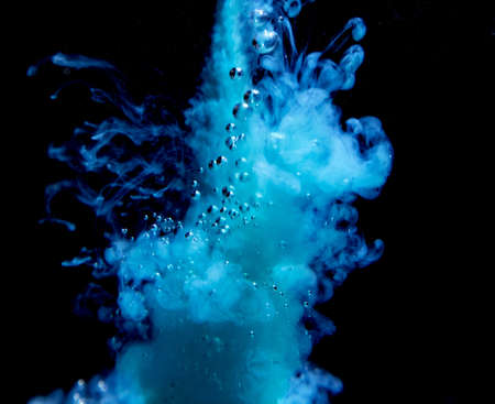 An abstract concept of blue color ink drop plume in water on an isolated  black background with...