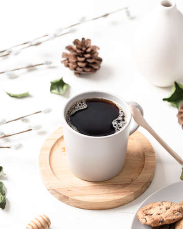 A vertical shot of a cup of coffee and cookies in a plate