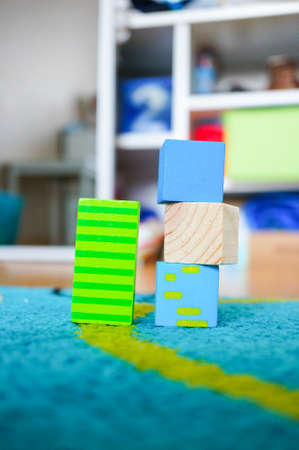 Square toys of multiple colors on top of each other on a multicolored carpetの写真素材