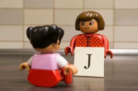 POZNAN, POLAND - Sep 17, 2017: Lego Duplo teacher woman  figurine showing letter J to sitting girl in soft focus.のeditorial素材