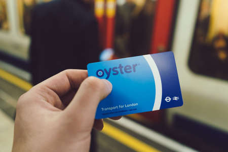 LONDON, UNITED KINGDOM - Nov 11, 2019: Male hand holding London Oyster card in public transport underground subway. Oyster card is used to use english public transport system.