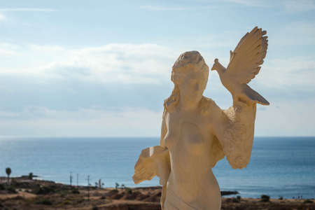 A statue of a woman with a bird in her hands during daytimeの写真素材