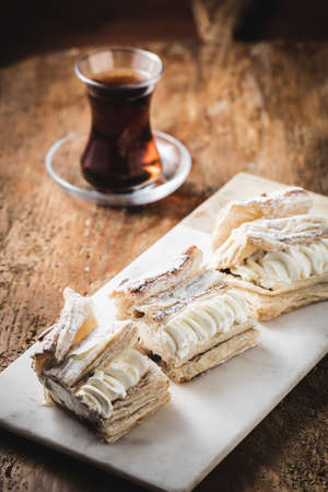 A beautiful shot of creamy dessert slices and a cup of tea next to itの写真素材