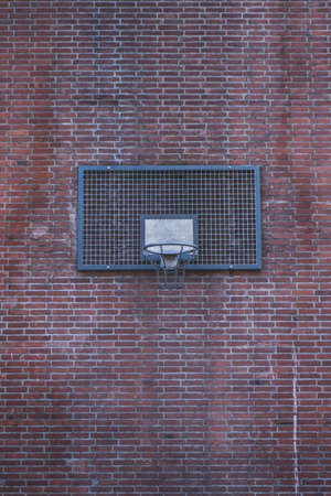 A wide shot of a basketball ring on a brick wall of a building