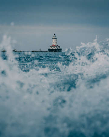 A vertical shot of a lighthouse through waves