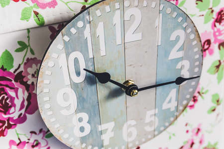 a grey clock on a background of pink flowers in soft focus