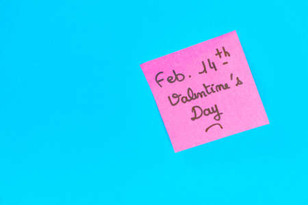 A closeup shot of a pink romantic Valentine's Day note on a blue surfaceの写真素材