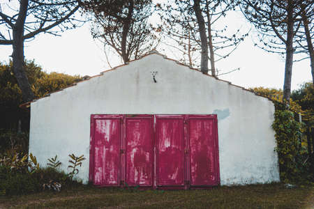 The beautiful view of an old white building with red gates in the woodの写真素材