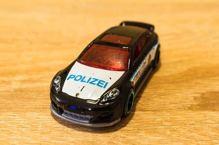 POZNAN, POLAND - Jun 02, 2020: Mattel Hot Wheels toy German police car on a wooden surface. Model of a Porsche Panamera. Horizontal high angle view.のeditorial素材
