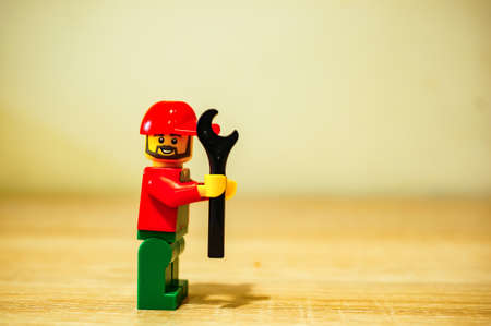 POZNAN, POLAND - Nov 09, 2019: Lego man figure holding a wrench in soft focus background.のeditorial素材