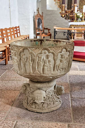 AAKIRKEBY, DENMARK - Jun 27, 2019: Aakirkeby, Bornholm island, Denmark - 27 June 2019. Sandstone baptismal font from 1200 in Aa Church (Aa Kirke) from the 12th centuryのeditorial素材