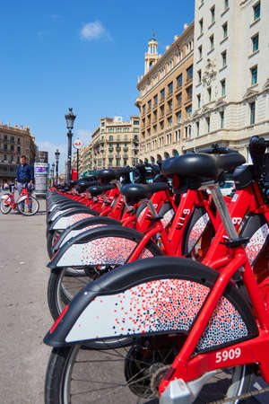 BARCELONA, SPAIN - Jun 07, 2019: Street transportation red hybrid rent bicycles with electronic form of payment for traveling around the city stand in row onのeditorial素材