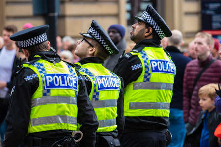 LEEDS, UNITED KINGDOM - May 05, 2019: 3 police officers in yellow vests watching the big screen at...