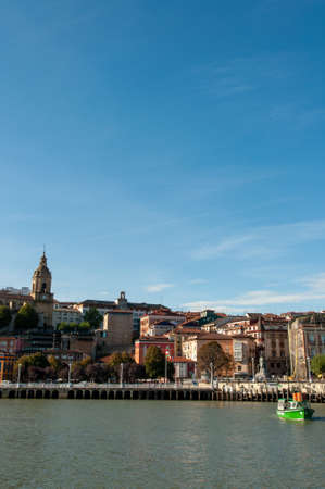 PORTUGALETE, SPAIN - Oct 24, 2009: A river surrounded by boats and buildings under a blue sky in Portugalete in Spainのeditorial素材