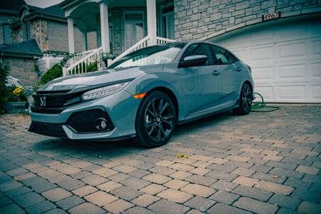 MONTREAL, CANADA - Oct 06, 2018: Blue/grey honda civic in a suburban driveway. Freshly cleaned showing the reflections of everything else nearbyのeditorial素材