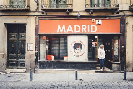 MADRID, SPAIN - Dec 09, 2015: glimpse of lady in front of a shop with a Madrid red sign  in the streets of the historic cityのeditorial素材