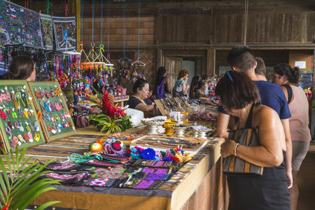 CACAO, FRANCE - Jul 25, 2019: Hmong woman selling handicrafts and tourists looking at objects offered for sale at a stall. Sunday Market, Cacao, French Guiana, Franceのeditorial素材