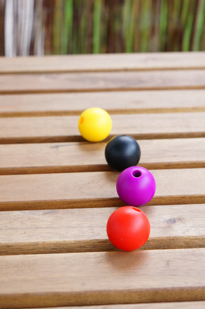 A vertical closeup shot of colorful beads on a wooden surfaceの写真素材