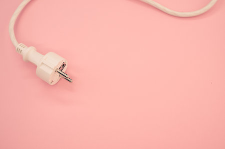 A high angle shot of an electrical wire and plug on a pink surfaceの写真素材