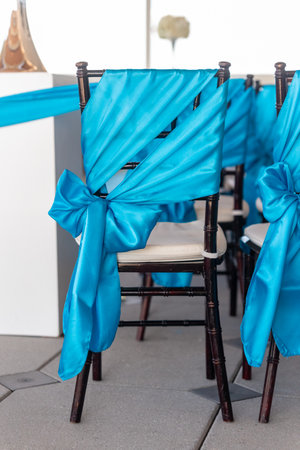 A closeup shot of the chairs decorated with turquoise bows in the wedding hallの写真素材