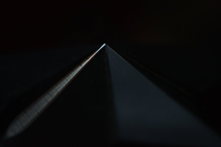 A closeup shot of a piece of metal in a pyramidal shape in the darknessの写真素材