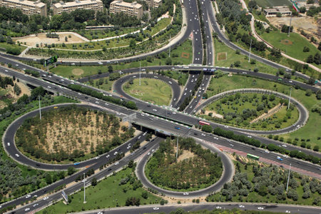 An aerial shot of a spaghetti junction with trees and grass next to it