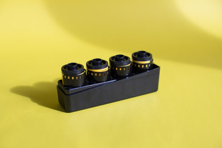 A high angle shot of four yellow and black filmstrips in a black box on a yellow surface