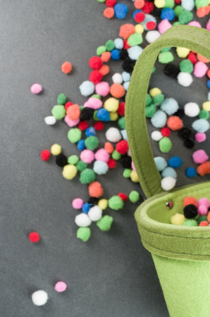 A vertical shot of colorful small cloth softballs on a green bucketの写真素材