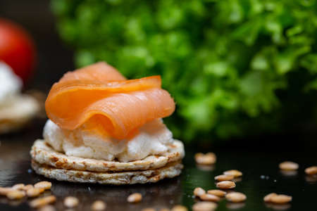 A closeup of salmon and cream cheese on a cracker on the table under the lightsの写真素材